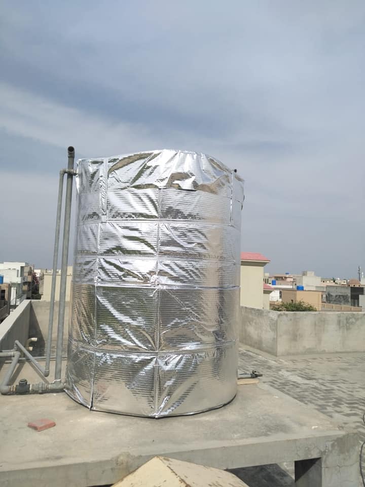 A cylindrical thermal insulated water tank cover with a reflective silver material, installed on a rooftop.